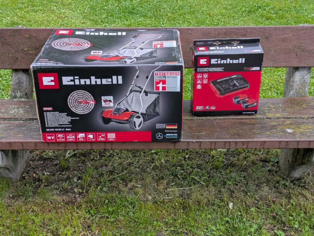 Verpackung des Einhell GE-HM 1838 Spindelmähers und des Ladegeräts mit Akku