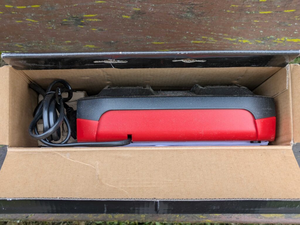 Verpackung des Ladegerätes und des Akkus des Einhell GE-HM 1838 Spindelmähers geöffnet